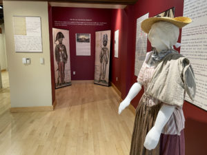 Signage and a dummy in historical dress in an indoor exhibit