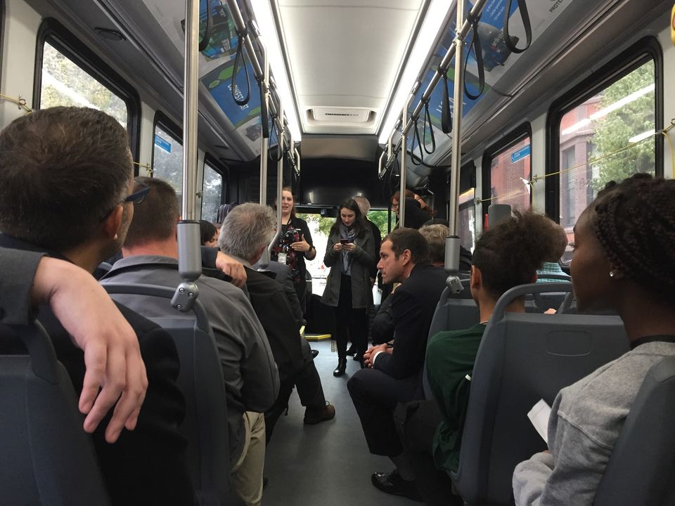 View from from the rear inside a bus of passengers seated and standing