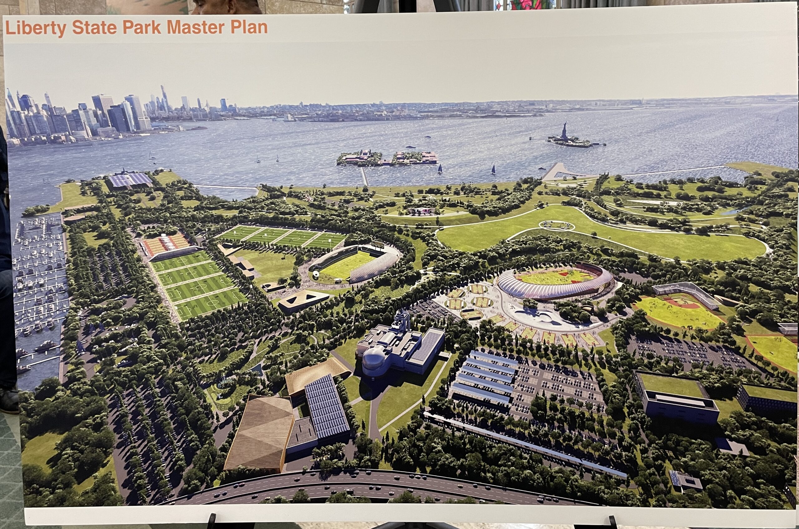 Poster labeled "Liberty State Park Master Plan" shows aerial view of a waterside park with fields, buildings, and natural spaces