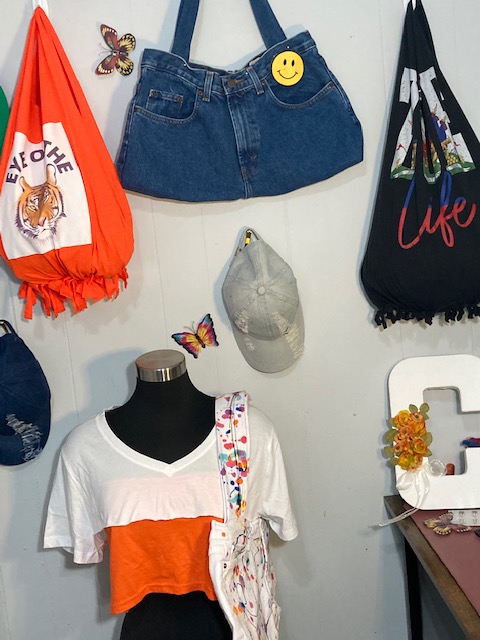Bags and a hat hang on a wall over a mannequin wearing a shirt