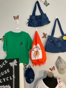 A shirt, hats, and bags hang from hooks on a wall