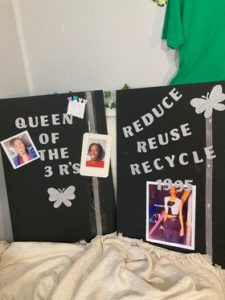 Signs state "Queen of the 3 R's" and "Reduce Reuse Recycle"