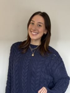 A young light skinned woman with brown hair, wearing a blue sweater