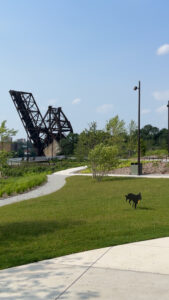 An X shaped metallic support towers over a waterfront park